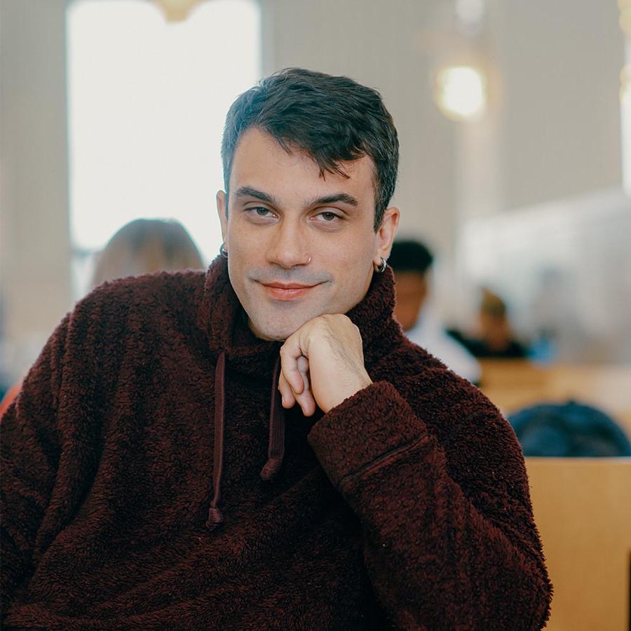 Stefan sits in the cafeteria looking thoughtfully at camera.